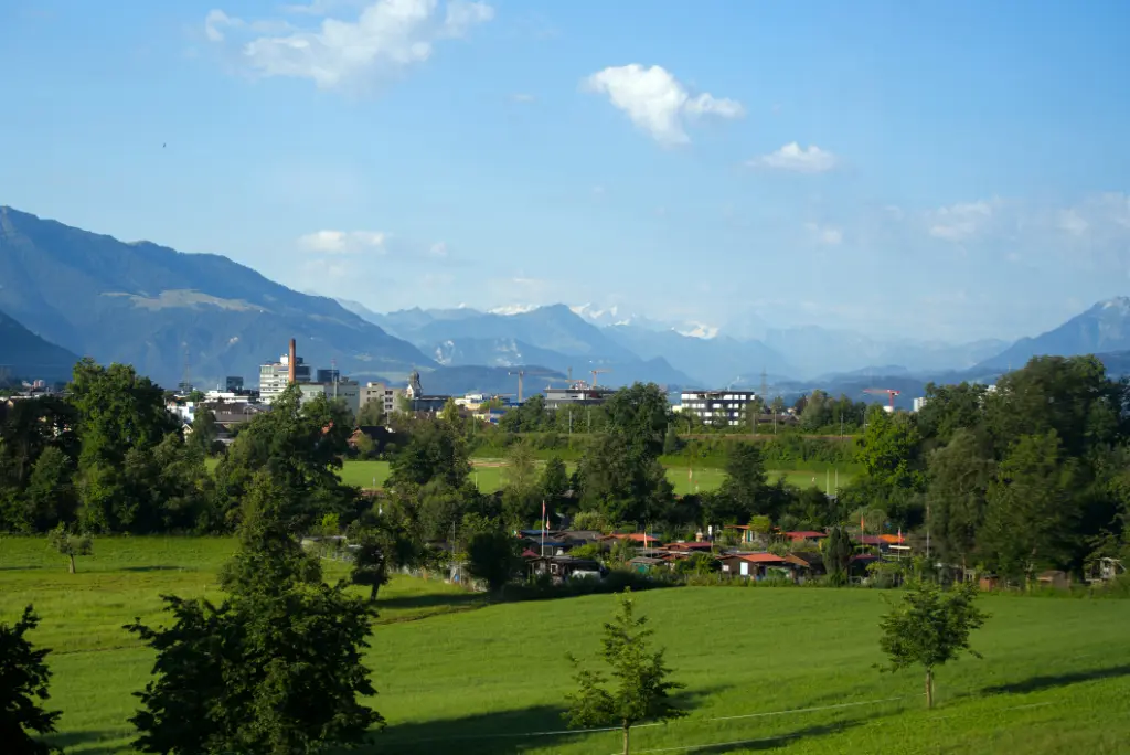 Skyline der Stadt Baar und Zug mit den Schweizer Alpen im Hintergrund an einem sonnigen Sommertag.